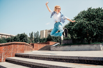 Charming girl woman jumping outdoors on steps under sunny weather showcasing urban lifestyle and happiness