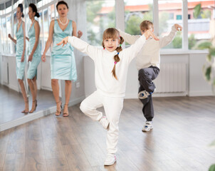 Boy and girl train to dance contemporary vigorous hip hop during classes. Female teacher conducts class for teen students during dance workout