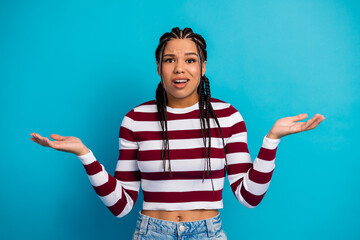 Young woman with braids wearing a striped maroon and white top stands against a blue background...