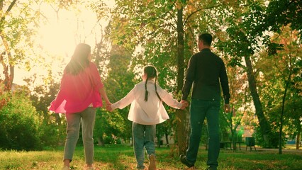 Parents child girl nature. Family, mom dad daughter walk together in summer park. Happy family, dad mom baby, walking hand in hand in city park sunset. Family outdoor recreation in autumn. Slow motion