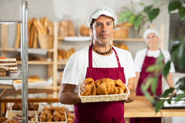 Man seller of bakery store is standing in trading floor, waiting for visitors, preparing to meet...