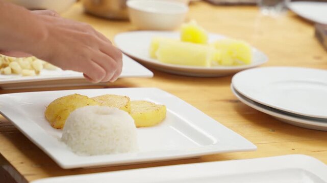 Chef arranging roasted potatoes and rice on plate