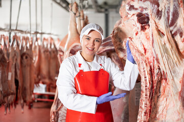 Female slaughterhouse worker showing beef chunk in meat storage