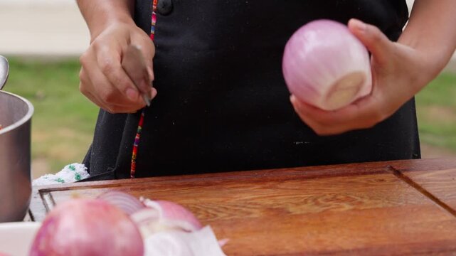 Peruvian chef peeling and cutting a red onion