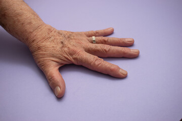 Elderly Hand on Lavender Surface