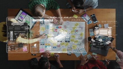 A dynamic collaboration scene showcasing a team engaged in brainstorming electric vehicle concepts with digital sketches and sticky notes spread across a wooden table. Raster
