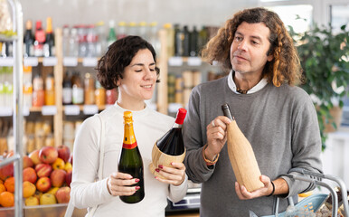 Husband and wife shopping together at the supermarket - choosing bottles of wine