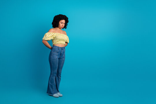 Portrait of a fashionable young female in summer attire posed against a vibrant blue background, exuding elegance and confidence