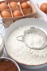 Ingredients for dough and strainer on white table, closeup