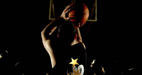 Preparing male athlete holding basketball above head at free-throw line, with gold star particles