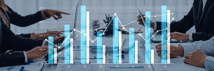 A professional business team collaborates in a modern office, analyzing financial data with graphs...