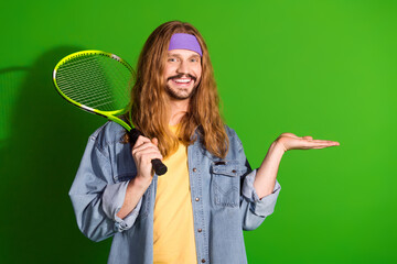 Young man with retro style holding a tennis racket and posing against vibrant green background,...