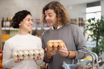 Married couple chooses eggs in a supermarket. Husband and wife buying farm eggs at a grocery store