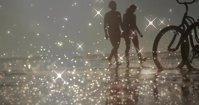 Sunlight shimmering on wet sand drawing senior man and son strolling past bicycle for beach leisure - Powered by Adobe