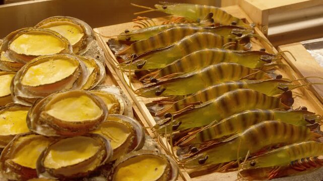 Fresh abalone and raw jumbo prawns displayed for sale in a seafood market