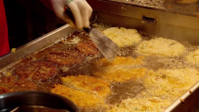 Hand frying traditional Korean bindaetteok pancakes on a hot griddle with oil
