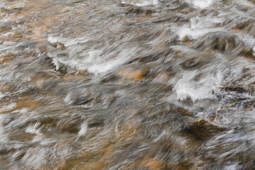 Abstract long exposure of flowing water in a river, motion blur texture background.