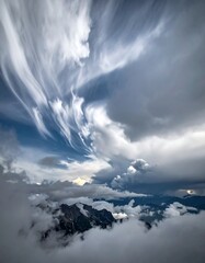 Naklejka premium Aerial view of wispy clouds with high peaks in the background