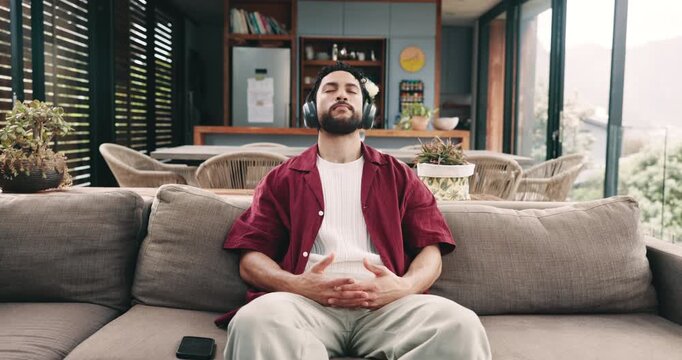 Phone, headphones and man meditate in home with music, peace and calm. Mobile, audio and person breathing to relax in living room for streaming, mindfulness podcast and listen to healing frequency