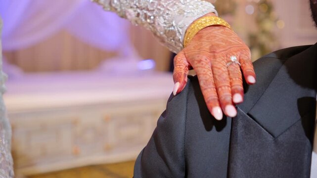 Bride Mehndi putting a hand with engagement ring on the groom shoulder while posing on Wedding Photoshoot cession