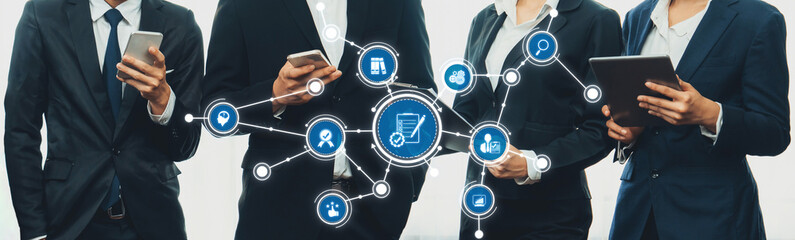 A group of business professionals engaging with digital devices, showcasing interconnected...