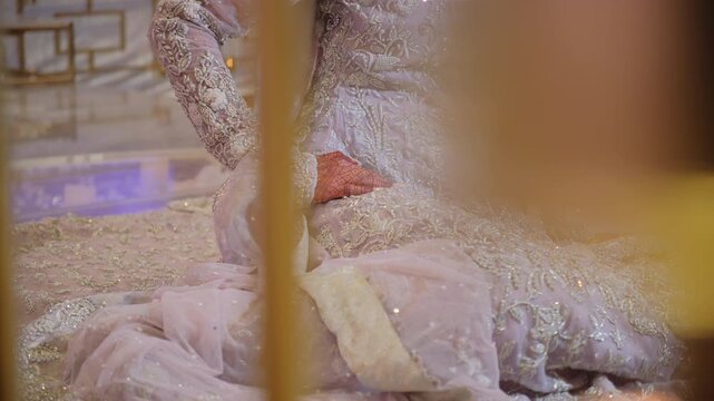 Bride, dressed in a traditional Pakistani wedding outfit, poses for the photographers