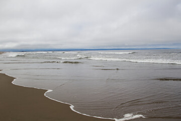 Ocean Waves Washing Over Sand Beach Overcast Sky