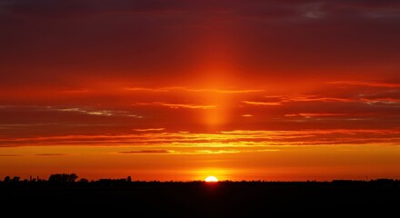 Intense fiery red sky illuminated by the setting sun, casting warm golden light across the distant horizon. A vivid, dramatic natural scene ,dramatic ,texture ,summer