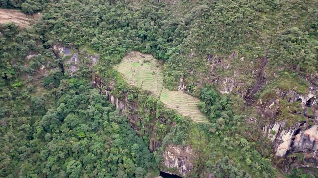 A smooth, low-altitude shot circles around vibrant green lower agricultural terraces of Machu Picchu, showcasing intricate stonework and the impressive engineering of ancient Inca farming system