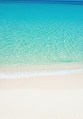 Crystal clear turquoise ocean water gently washing over pristine white sand on a tranquil beach, creating a seamless gradient of blue and white ,pristine ,texture ,depth