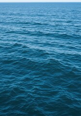 Fototapeta premium A boundless expanse of deep azure oceanic water stretches toward the distant horizon under a bright midday sun, featuring gentle rolling waves ,serenity ,daylight ,wave