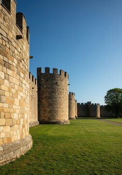 Ancient stone walls of a massive European style castle standing tall against the horizon, showcasing defensive architecture and history ,tower ,majestic ,royal