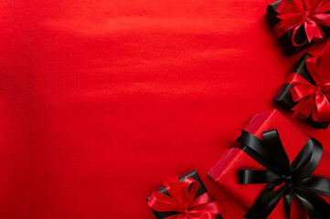 Black Friday concept with a corner frame of red and black gifts on a vibrant red background for sales banners.