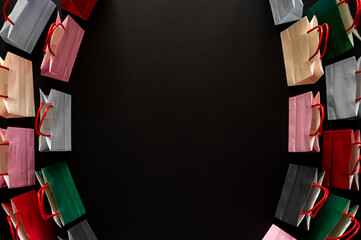 Black Friday concept with colorful shopping bags with red handles on dark black background for sales text.