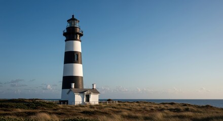Tall historic coastal lighthouse featuring prominent black and white bands, providing navigational assistance for ships near the Atlantic shoreline ,coast ,shoreline ,sky
