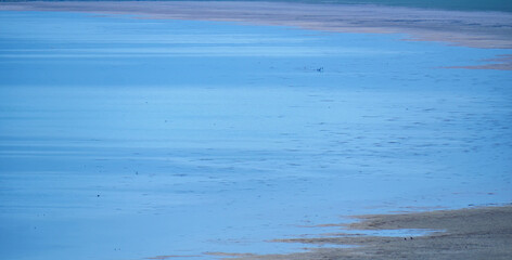 A minimalist abstract background of a calm blue lake surface with the soft light creating a beautiful and serene gradient