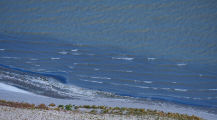 An abstract texture of the surface of a calm lake with gentle waves and patterns on the shoreline creating a beautiful natural background