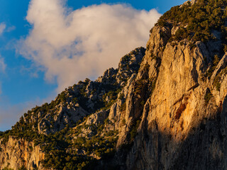 A dramatic mountain peak is lit by the warm golden hour light creating a strong contrast with the dark shadow on the cliff face