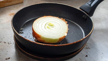 A raw onion slice is prepared in a non-stick frying pan