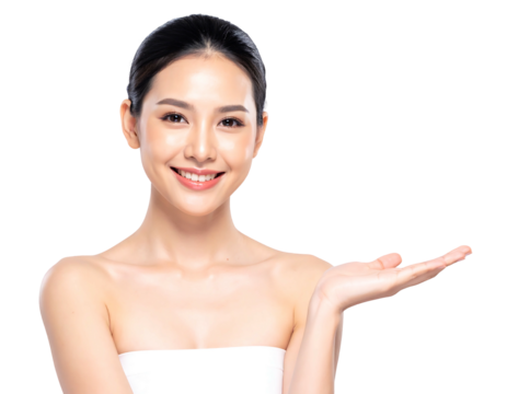 Radiant, smiling Asian woman presents with open hand, bare shoulders against black background. Gentle light, flawless skin