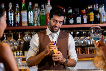 A charismatic bartender or mixologist smiles at a customer while preparing a craft cocktail with a shaker A concept for the hospitality industry and expert service