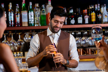 A charismatic bartender or mixologist smiles at a customer while preparing a craft cocktail with a shaker A concept for the hospitality industry and expert service