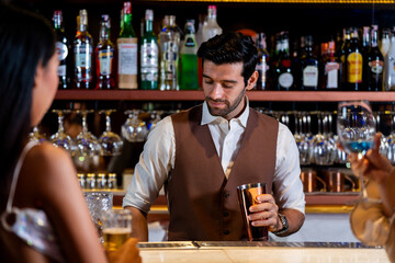 A charismatic bartender or mixologist smiles at a customer while preparing a craft cocktail with a shaker A concept for the hospitality industry and expert service