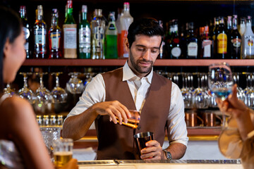 A charismatic bartender or mixologist smiles at a customer while preparing a craft cocktail with a shaker A concept for the hospitality industry and expert service