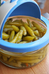 Green chili peppers in a glass jar with a blue lid