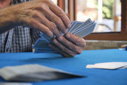 Senior man plays cards at a table in bright room - Powered by Adobe