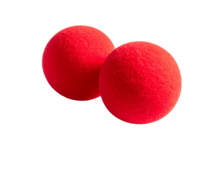 Two bright red fuzzy balls rest slightly overlapping on a stark black background, highlighted by warm light