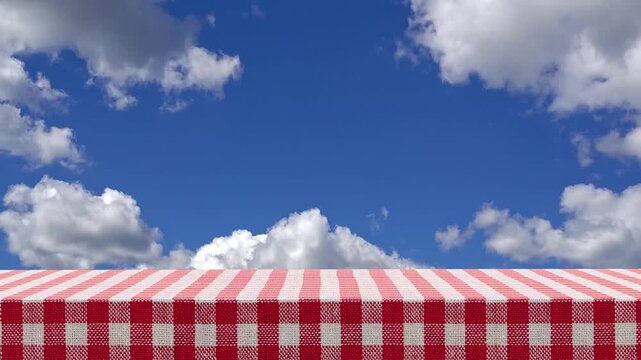 4k Resolution Video: Outdoor Picnic Concept. Red And White Checkered Tablecloth With Blue Sky And White Moving Clouds In The Background