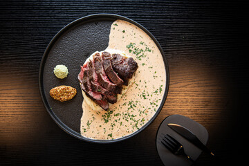 Gourmet Sliced Steak with Creamy Sauce and Mashed Potatoes on a Dark Table