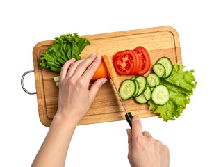 Overhead view of hands cutting vegetables on a wooden cutting board with lettuce, tomato, and cucumber slices
